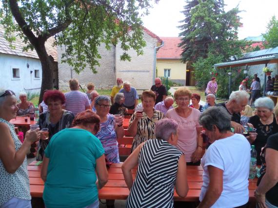 Seniori majú prípitok za stolmi v záhrade Denného centra Seniori majú prípitok za stolmi v záhrade Denného centra